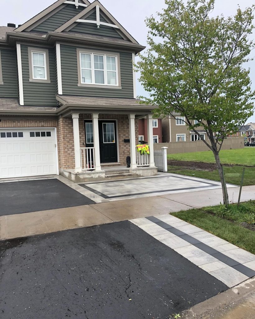 Front of a two-storey house with a bordered paver landing at the porch and a banded paver strip crossing the walkway