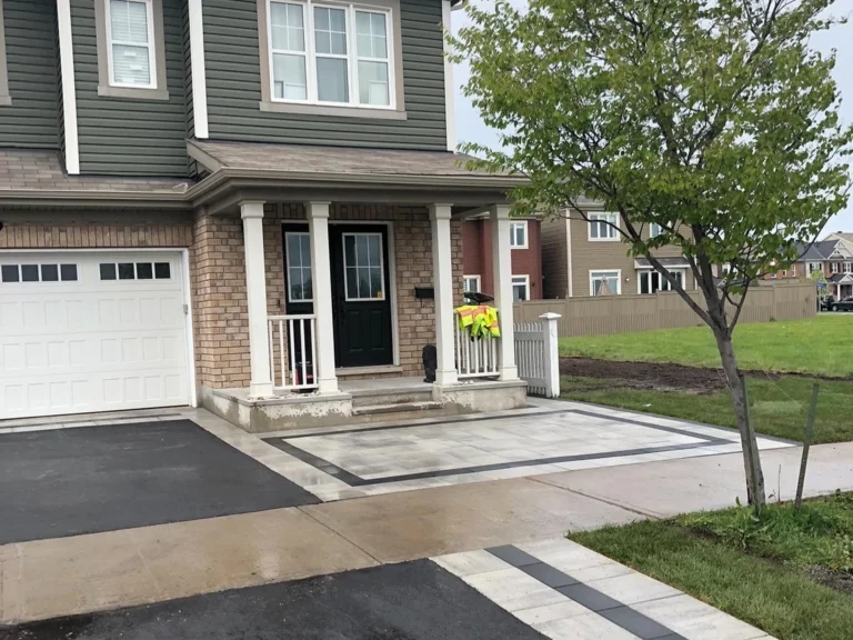 Front of a two-storey house with a bordered paver landing at the porch and a banded paver strip crossing the walkway