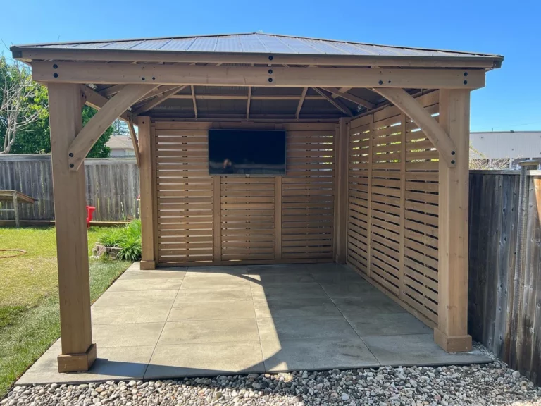 Timber pavilion with a metal roof over a slab patio in a fenced backyard